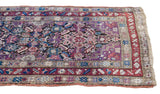 Close-up of antique Caucasian rug: serrated leaf design and starburst borders in violet, aubergine, indigo.