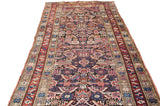 Angled close-up of antique Caucasian runner's geometric starbursts and serrated leaf motifs.