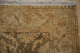 Corner of the gold wash Indian rug showing the soft full pile, floral palmette border, and ivory fringe.