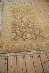 Angled view of the gold wash Oushak rug, showing the floral border, soft pile, and ivory fringe.