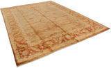 Full length diagonal view of a lustrous Indian Oushak carpet in gold and rust tones.