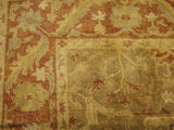 Corner of an Oushak carpet with a copper-colored serrated leaf border against the golden sage field.