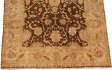 Angled corner view of a gold wash Oushak carpet's meandering vine and floral border.
