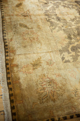 Dusty gold Oushak carpet border with brown palmettes, floral vinery, and fringe.