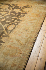 Oushak design carpet with meandering vine border and golden floral motifs on a charcoal field.