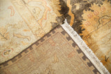 Folded Indian Oushak carpet revealing gold, brown floral pile, hand-knotted foundation, and fringe.
