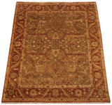Indian Oushak carpet from an angle, showing its rust palmette border and golden olive floral field.