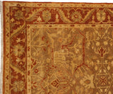 Corner of an Oushak carpet showing the meandering vine and palmette border in rust and dusty gold tones.