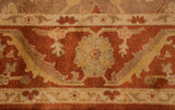 A floral palmette motif on the main border in copper, rust, and dusty gold hues.