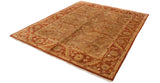 Angled view of an Indian Oushak rug with a rust border and golden-green field.