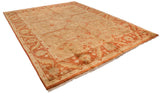 Angled view of a gold wash Indian Oushak carpet with rust and terracotta floral patterns.