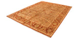 High-angle view of the Oushak design carpet, showing its golden field, rust palmette border, and soft pile.