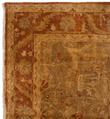 Corner of an Oushak rug showing the meandering vine border in rust, gold, and olive tones.