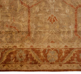 Close view of the Indian Oushak rug's terracotta border with palmette and vine motifs.