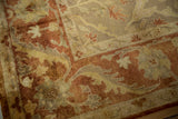 Plush, hand-knotted pile showing the meandering vine border in rust, copper, and golden olive tones.