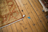 Hand-knotted corner of an Oushak design carpet showing the attached product tag and ivory fringe.
