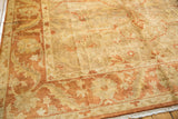 Angled view of an Oushak rug corner showing the soft pile, palmette border, and ivory fringe.