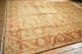 Angled view showing the polished sheen of a gold wash Oushak carpet with a rust and palmette border.