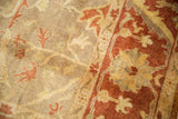 Soft pile detail of a rust-colored border with golden palmettes and floral vinery.