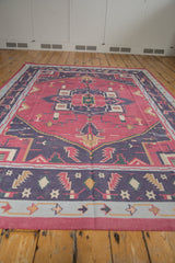 Low angle view of a vintage Dhurrie's raspberry field and geometric navy blue medallion.