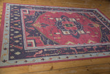 Perspective view of a vintage Dhurrie carpet with a raspberry field and navy geometric borders.