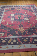 Low angle view of the geometric medallion on a raspberry and navy vintage Dhurrie rug.