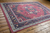 Angled perspective on a vintage Dhurrie with raspberry, navy, and slate blue geometry.