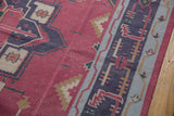 Geometric motifs in raspberry, navy, and powder blue on a vintage handwoven Dhurrie carpet.
