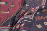 Folded vintage Dhurrie carpet showing contrasting raspberry and violet-navy geometric patterns.