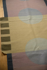 Abstract kilim weave showing roundel motifs in beige, mauve, and pale blue.