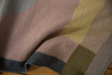 Contemporary kilim rug with textured fold highlighting mauve, olive, and dark blue blocks.
