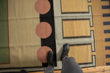 Hand-woven vintage Kilim rug detail, showing abstract geometric pattern, cinnabar circles, and slate frames.