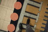 Contemporary kilim with abstract pale cinnabar red circles and black 'track trail' patterns.