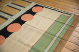 Abstract contemporary kilim with pale red circles, black 'track trails,' ivory, green.