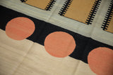 Abstract kilim showing pale cinnabar red circles, black tracks, and neutral panels.