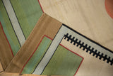 Folded corner of contemporary kilim, showing flatweave, side cord, and geometric black, green, beige design.