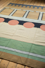 Contemporary kilim carpet with geometric bands of sand, emerald green, silver, and dusty gold.