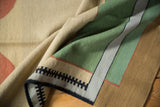 Vintage contemporary kilim corner featuring geometric black border and sand, emerald green, gold blocks.
