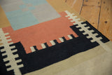 Stepped geometric blocks of contemporary Kilim rug in black, red, beige, and blue.