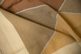 Modern Indian Kilim carpet, folded, showing Argyle pattern in copper, beige, and ivory.