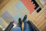 Abstract pinwheel pattern of a contemporary Kilim runner in sand, blue, coral, black, lilac.
