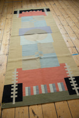 Close-up of the kilim's abstract geometric blocks in coral, black, sand, ivory, and olive green.