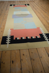 Secured side edge of a contemporary kilim runner with geometric coral, black, and sand design.