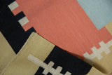 Folded corner of contemporary kilim rug with geometric madder root red, black, sand pattern.