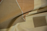 Folded hand-woven kilim with argyle pattern in copper, sand, and ivory tones.