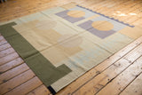 Abstract contemporary kilim featuring pale yellow circles and grey-purple geometric pattern.