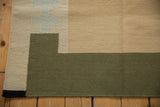 Side edge of contemporary Kilim flatweave with beige, pale blue, and olive geometric blocks.