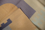Flatweave Kilim carpet corner showing original side cord selvage and geometric design in beige, dusty blue.
