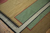 Corner of vintage kilim rug, highlighting a small repaired cut and black geometric pattern.