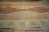 Hand woven contemporary kilim carpet detail: copper, gold, and beige argyle pattern with a visible repair.